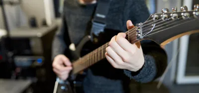 Guitarist with fingers fretting chords on an acoustic guitar neck