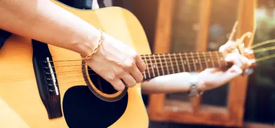 Beginner guitarist playing an easy 3-chord song on acoustic guitar