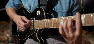 Guitarist fretting a barre chord on an acoustic guitar