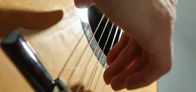Hands playing a nylon-string classical guitar