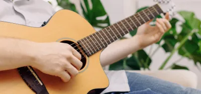 Beginner playing four strings on an acoustic guitar