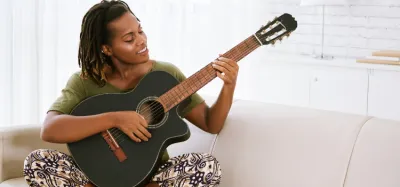 Beginner practicing a single guitar chord on an acoustic guitar