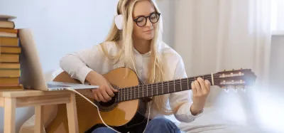 Beginner practicing four-chord songs on an acoustic guitar