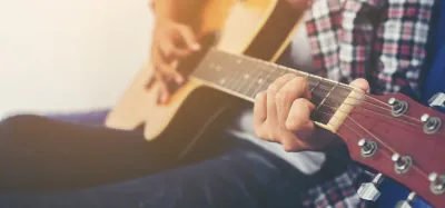 Beginner practicing easy two-string songs on an acoustic guitar
