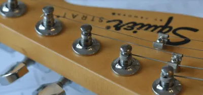 Squier Stratocaster electric guitar laid out for upgrades and modifications