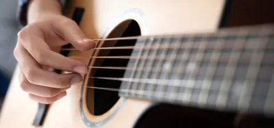 Taylor acoustic guitar resting against a wall, showing its wood grain and body shape