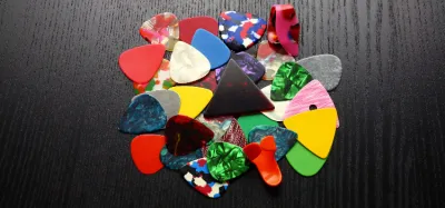 A selection of the best thick guitar picks fanned out on a wooden surface
