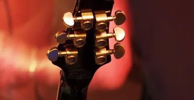 Close-up of guitar locking tuners on a headstock showing the clamping mechanism
