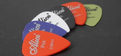 Hand using a flat pick to play steel strings on an acoustic guitar