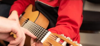 Young child holding a small-size acoustic guitar sized for a 6 to 10 year old