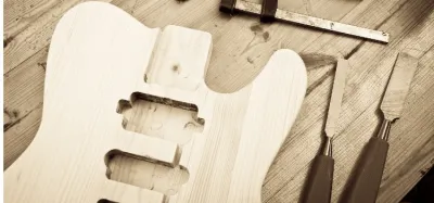 Luthier working on a partially built guitar body in a workshop
