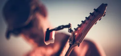Close-up of a guitar headstock and tuning pegs being adjusted